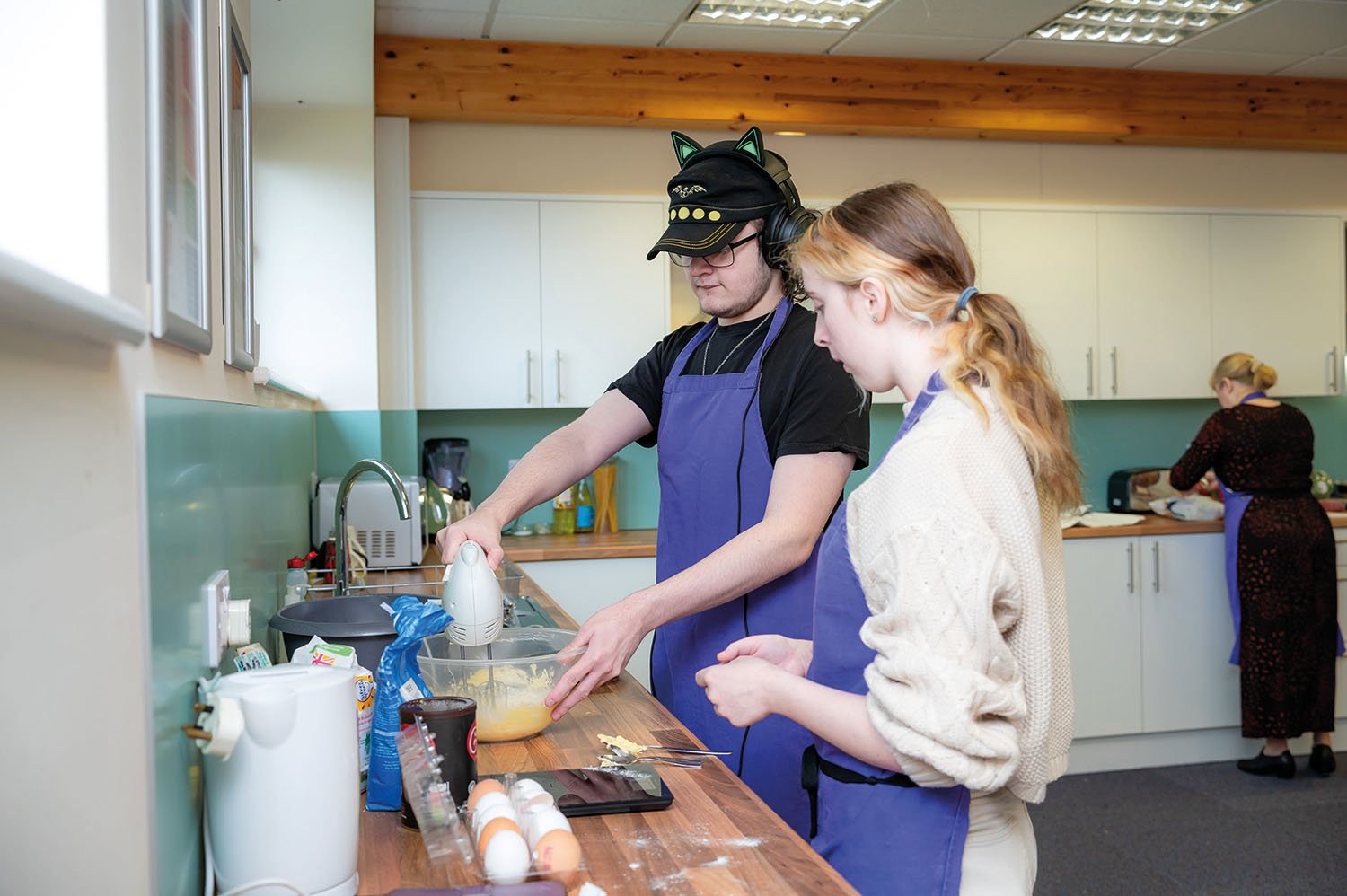two students using a whisk in a kitchen area at our Downham Market site