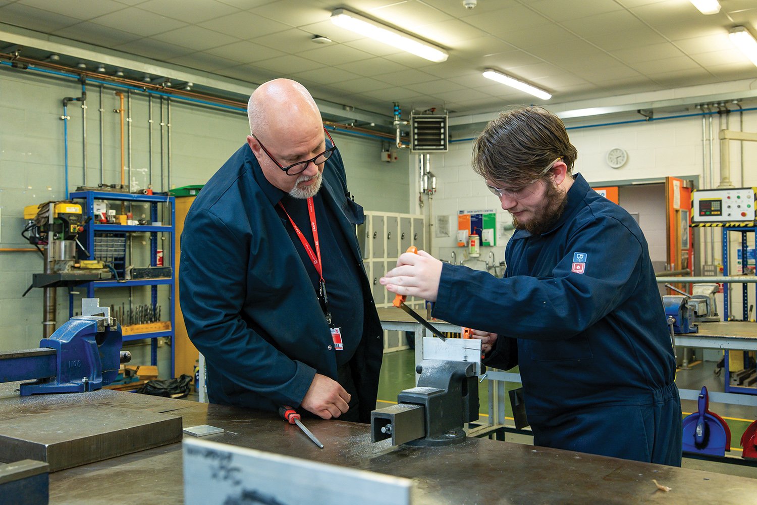 Engineering tutor teaching a student how to use a hack saw